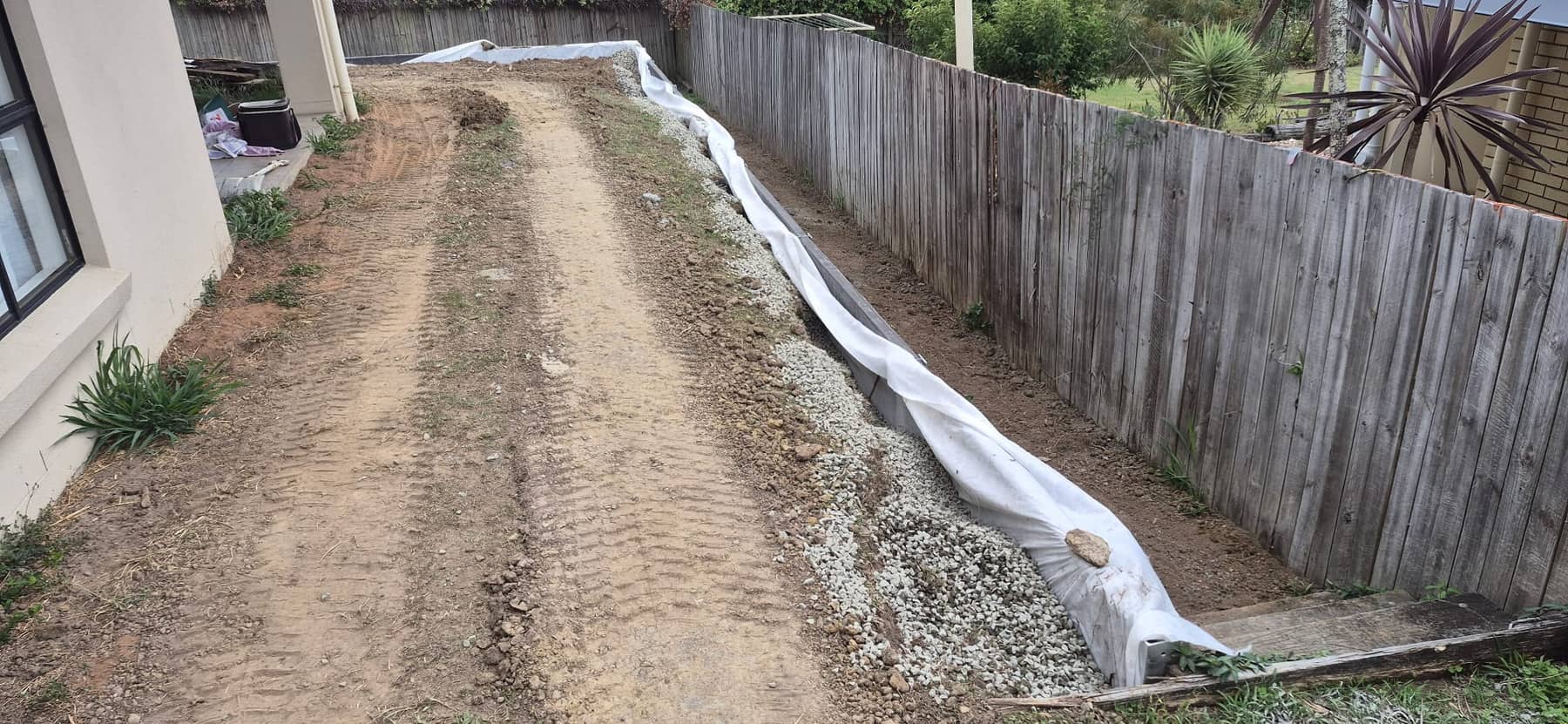 The new sleeper wall down the side of the house, with gravel wrapped in white fabric behind it