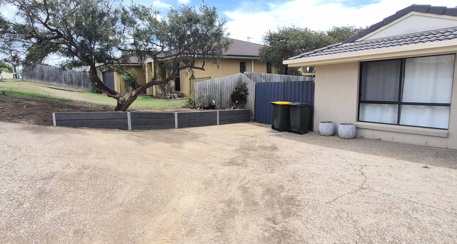 The finished concrete sleeper wall around the tree bed beside the driveway