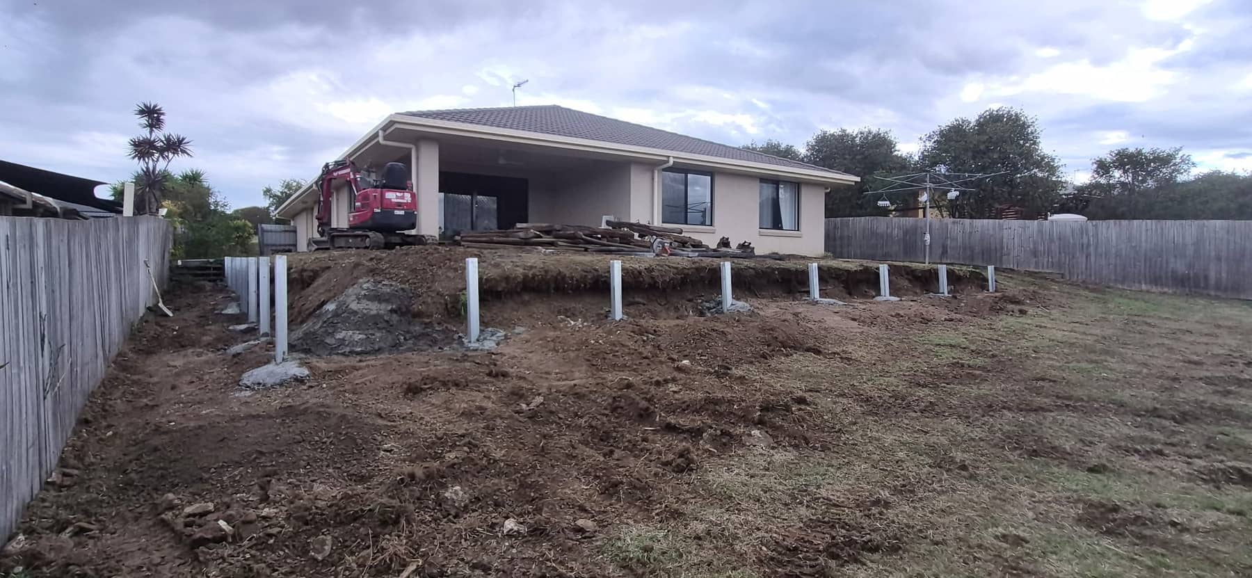 New steel posts set in concrete along the line of the back wall