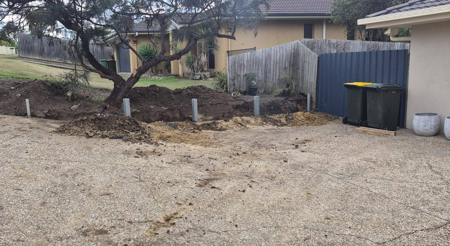 New steel posts set in concrete along the driveway edge of the front bed