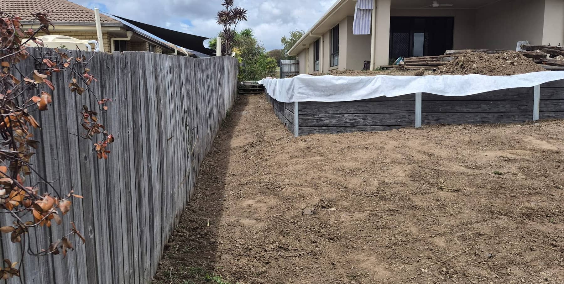 Concrete sleepers in between the posts at the back, with white fabric behind them, folded over the top
