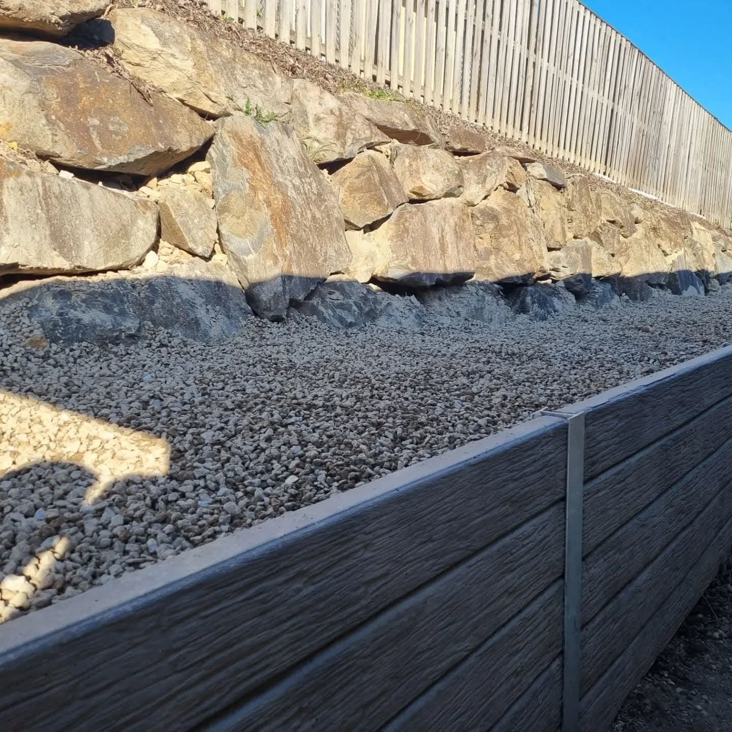 Drainage gravel backfilled behind the new sleepers, below the rock wall