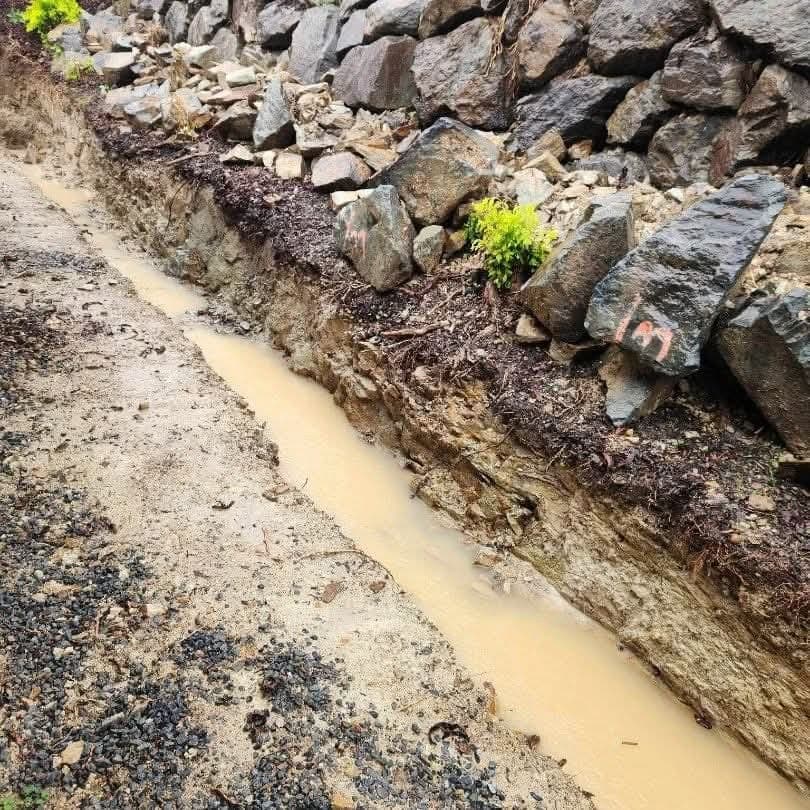 A trench cut along the foot of the rock wall, with water sitting in it